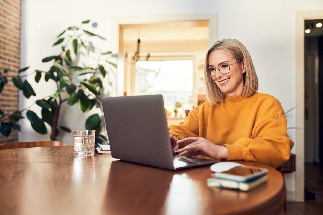Young woman is using a laptop while smiling
