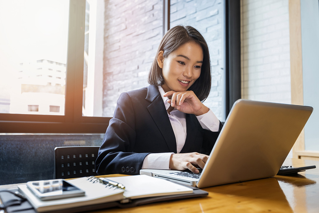 Woman wearing suit on laptop in office