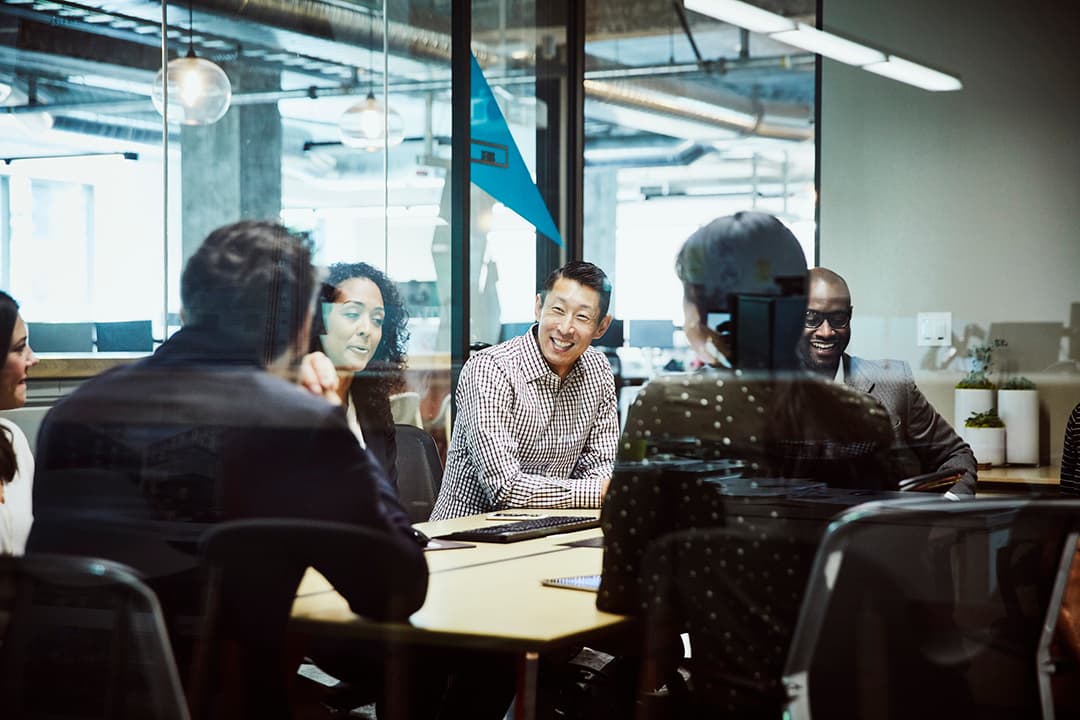 Six people sitting around a table in the workplace