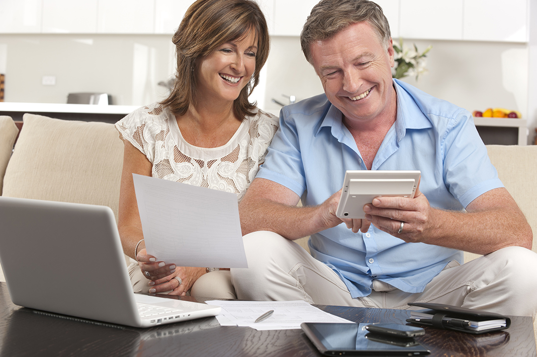 Image of couple on couch with a laptop and calculator