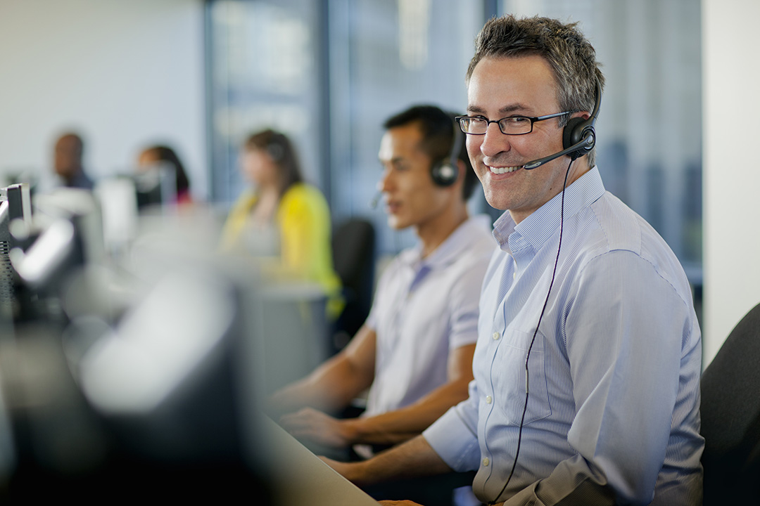 Man with glasses in call centre wearing a headset