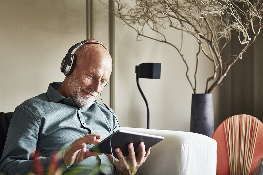 Senior man holding tablet wearing headphones