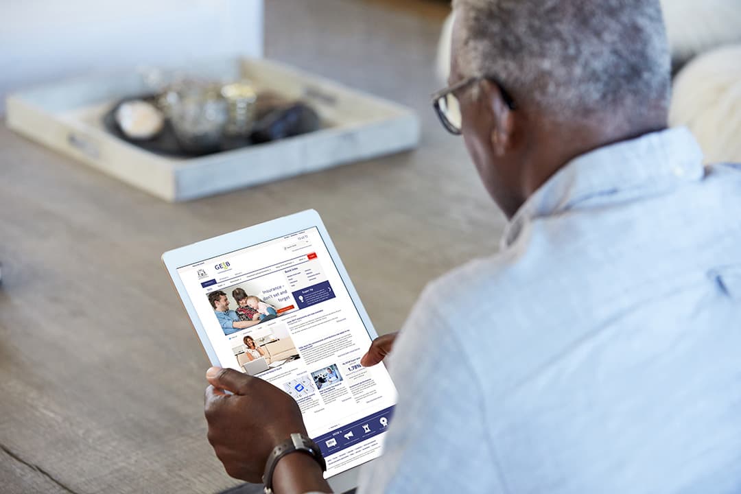 Senior man holding tablet showing GESB homepage