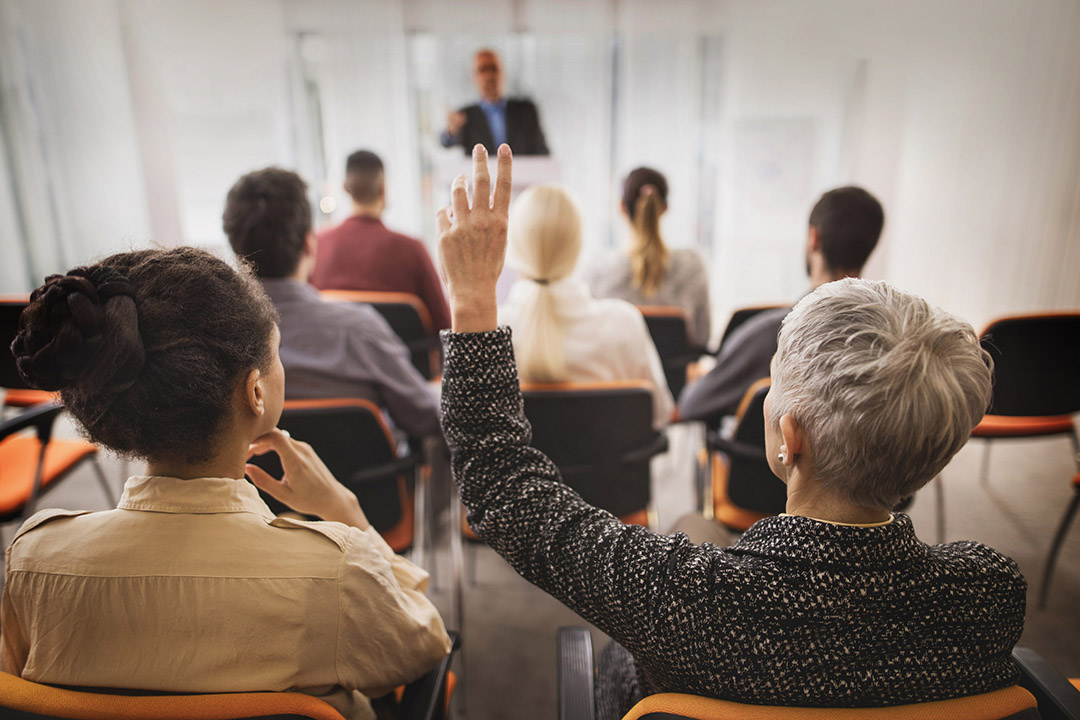 Seminar: older lady with hand up
